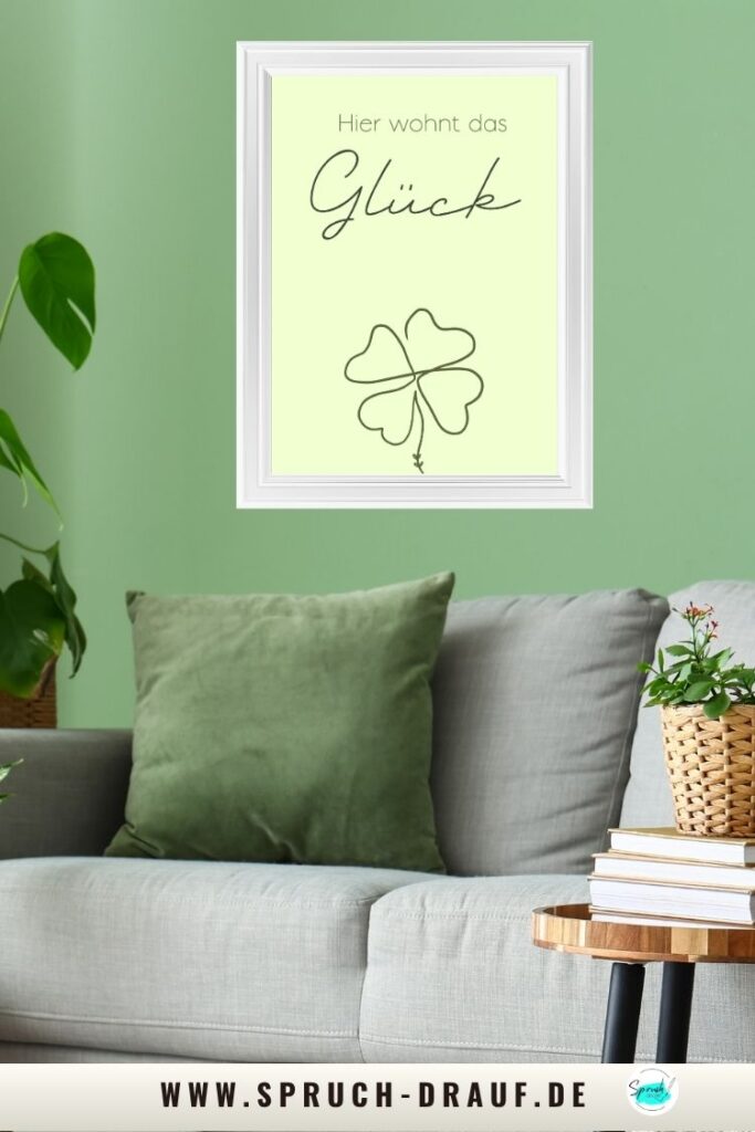 Poster „Hier wohnt das Glück“ in einem grünen Wohnzimmer mit Pflanzen